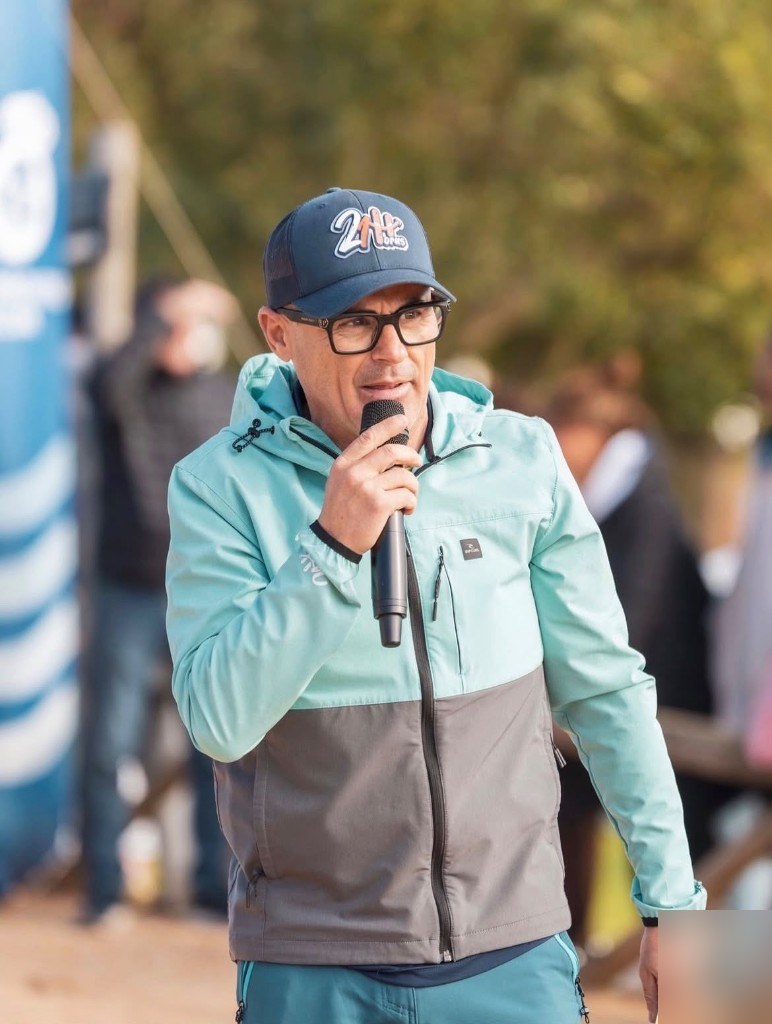 Ernesto 21h, speaker oficial de la Grinch Run, habla al público con un micrófono.